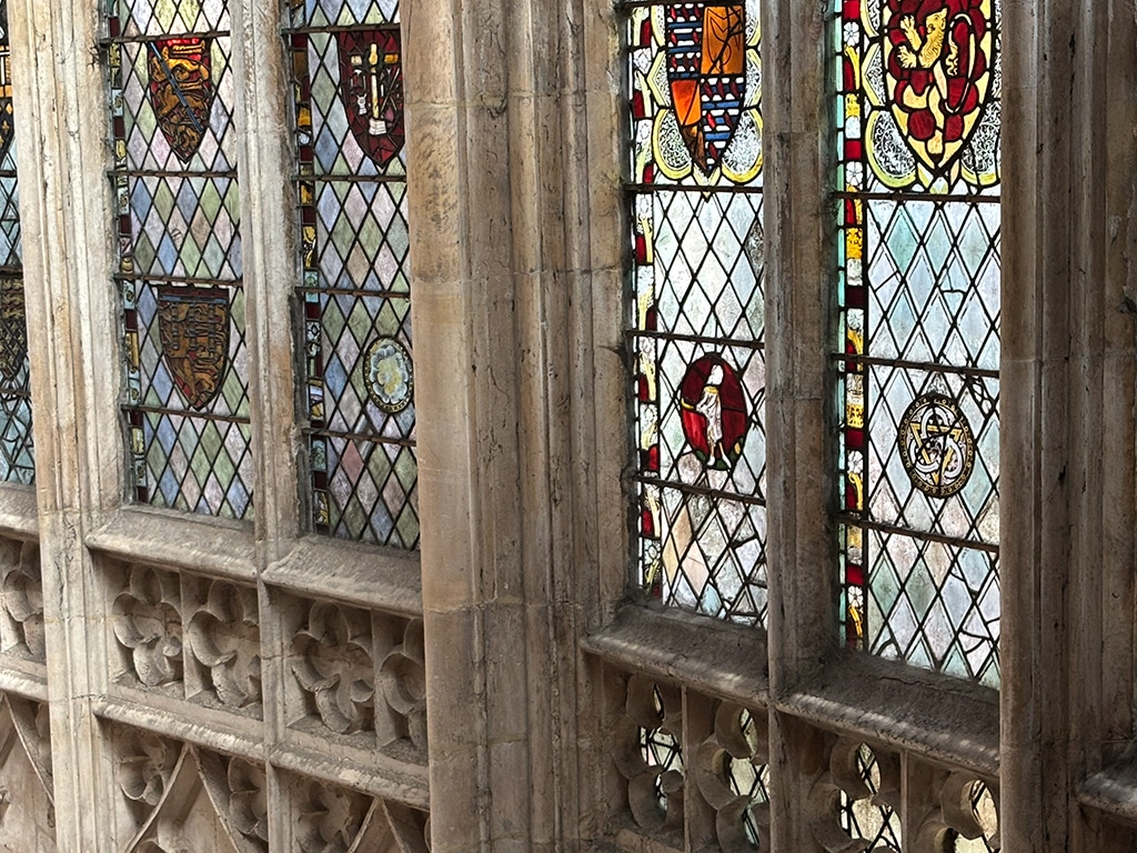 Large stained glass windows arranged in a diamond pattern with circular and shield-shaped central imagery