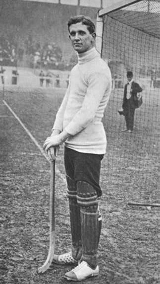 A black and white photo of a man, England goalkeeper Harvey Wood, wearing specialist hockey boots with extra protection on the instep, 1908.