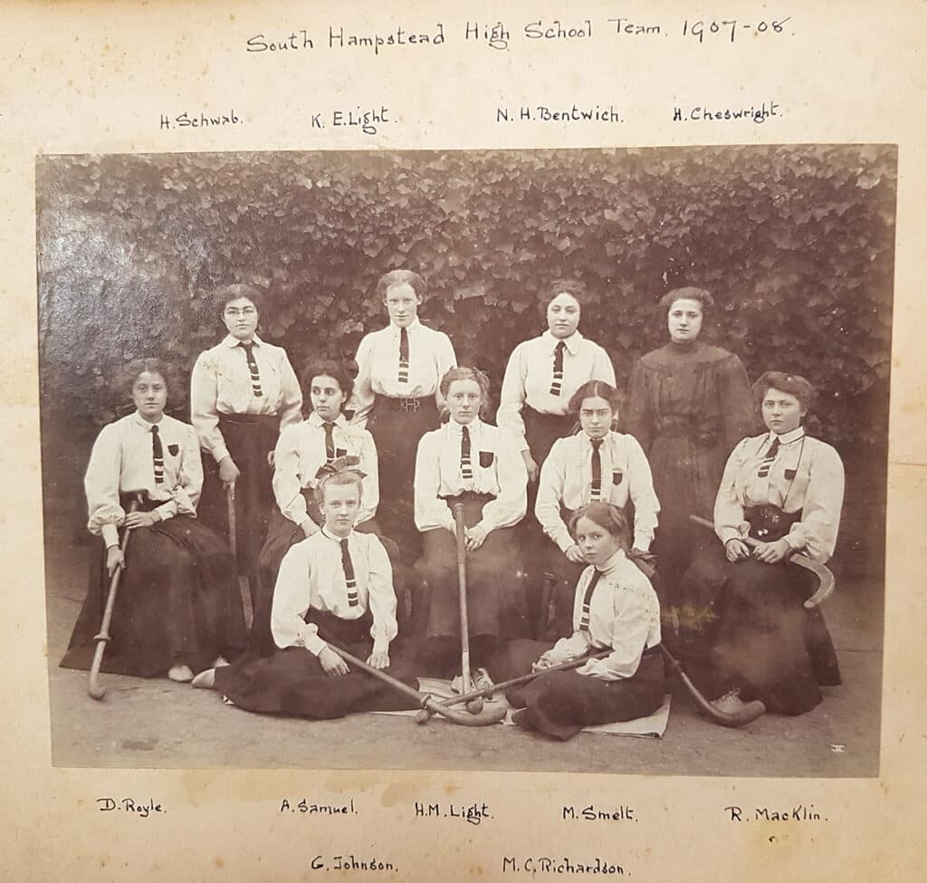 A black and white image of a women's hockey team and their sticks