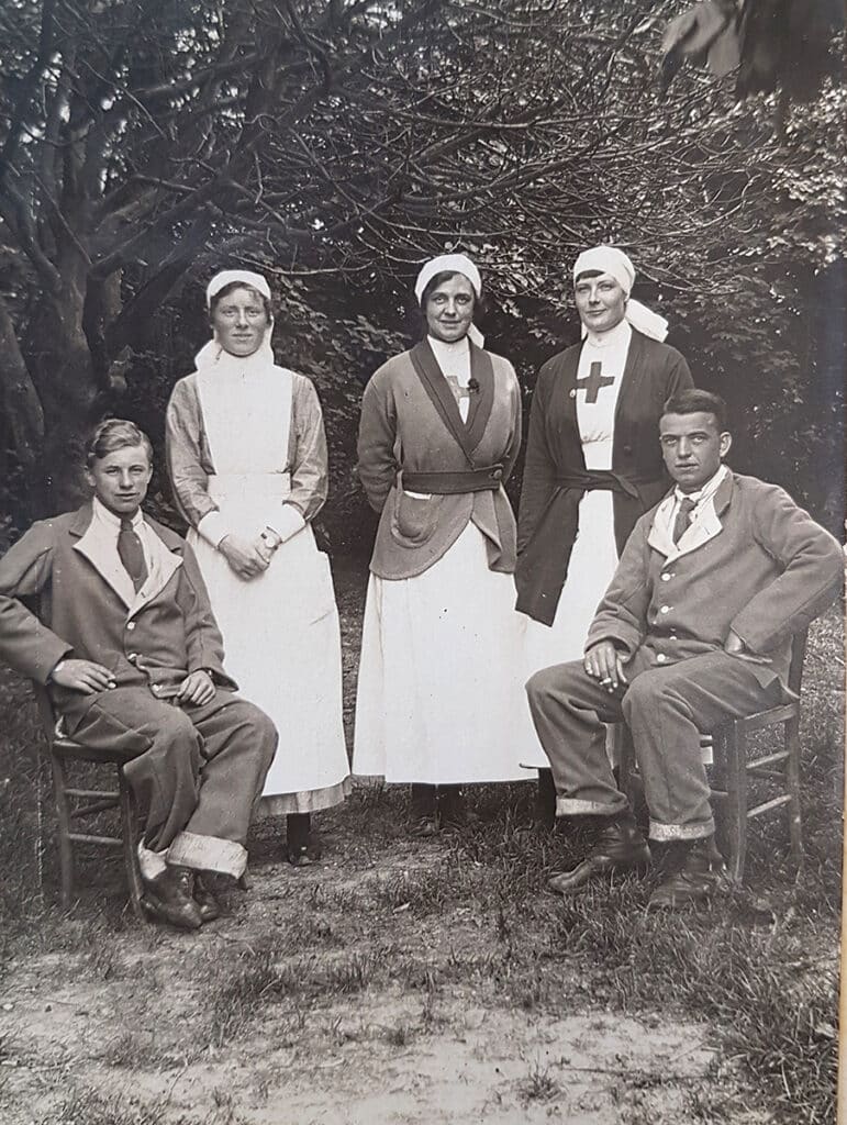 A black and white image of two men either side of three women who are wearing nurses uniforms