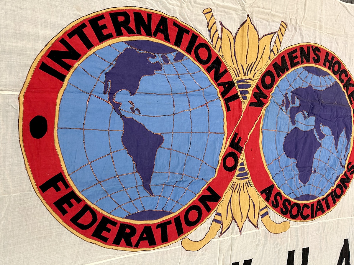 The detail of the applique on the IFWHA flag, showing two globes, one of The Americas, the other the Rest of the World and the words International Federation of Women's Hocket around them.