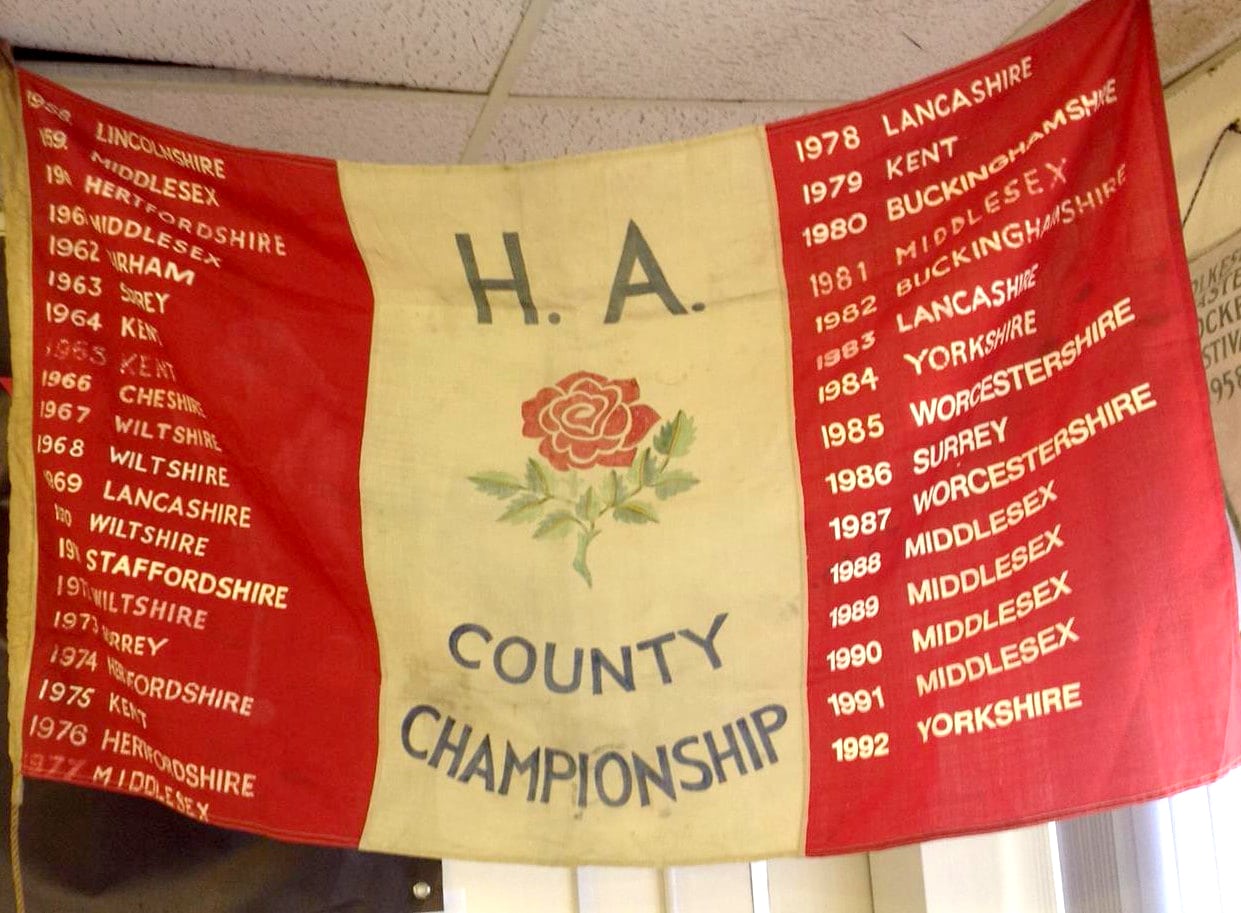 A colour image of the HA County Championship flag, which is a red and white flag with a red rose in the middle.