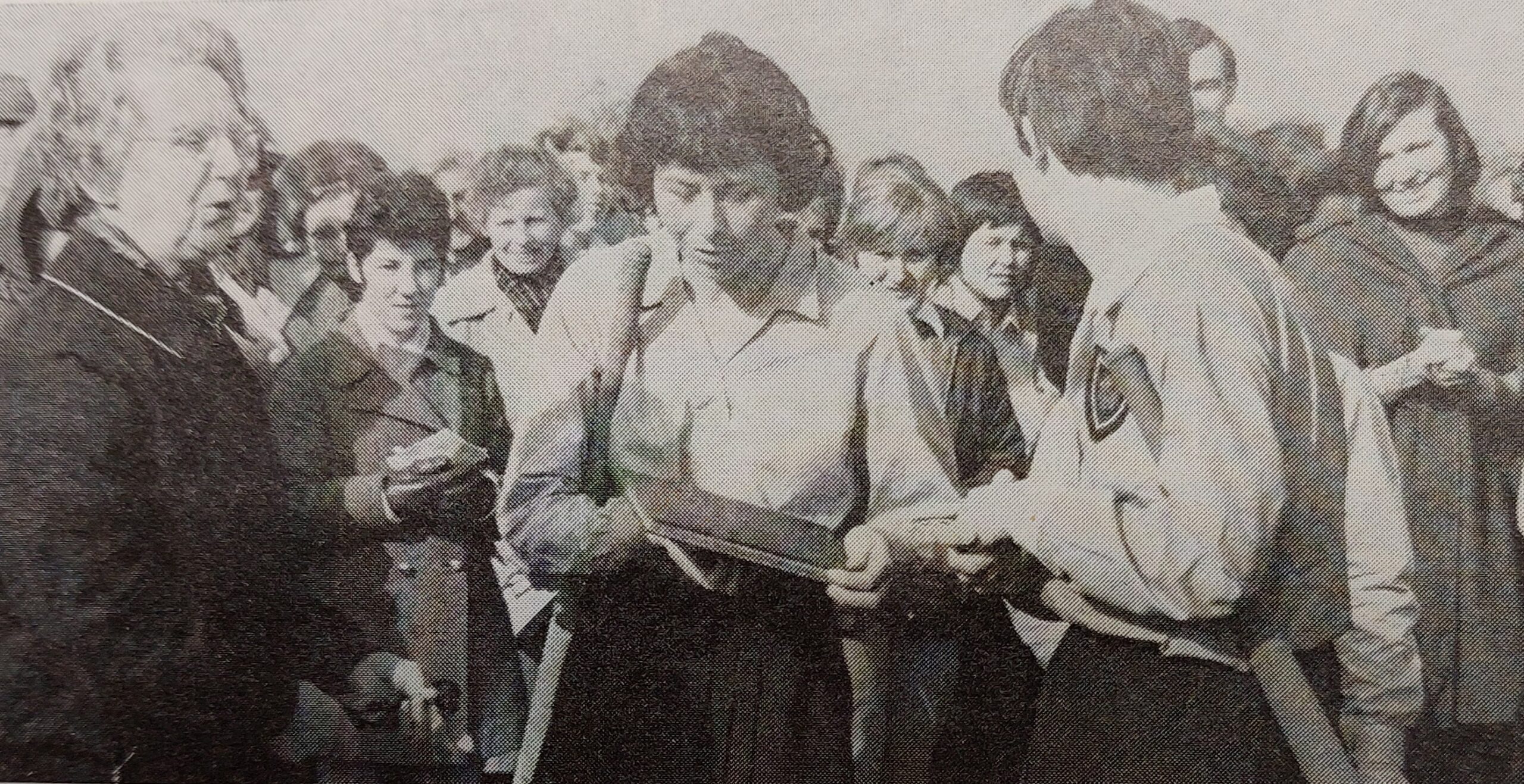 A black and white photo of two female hockey players being presented with an album