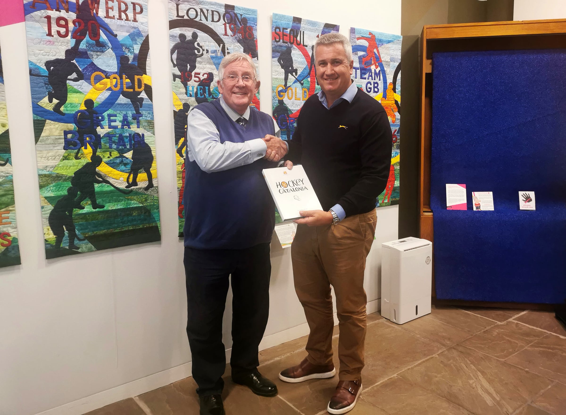 Two men smiling at the camera holding a book