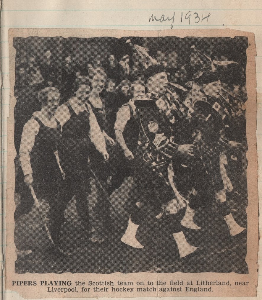 A black and white newspaper image of a hockey team with bagpipers leading them onto the pitch