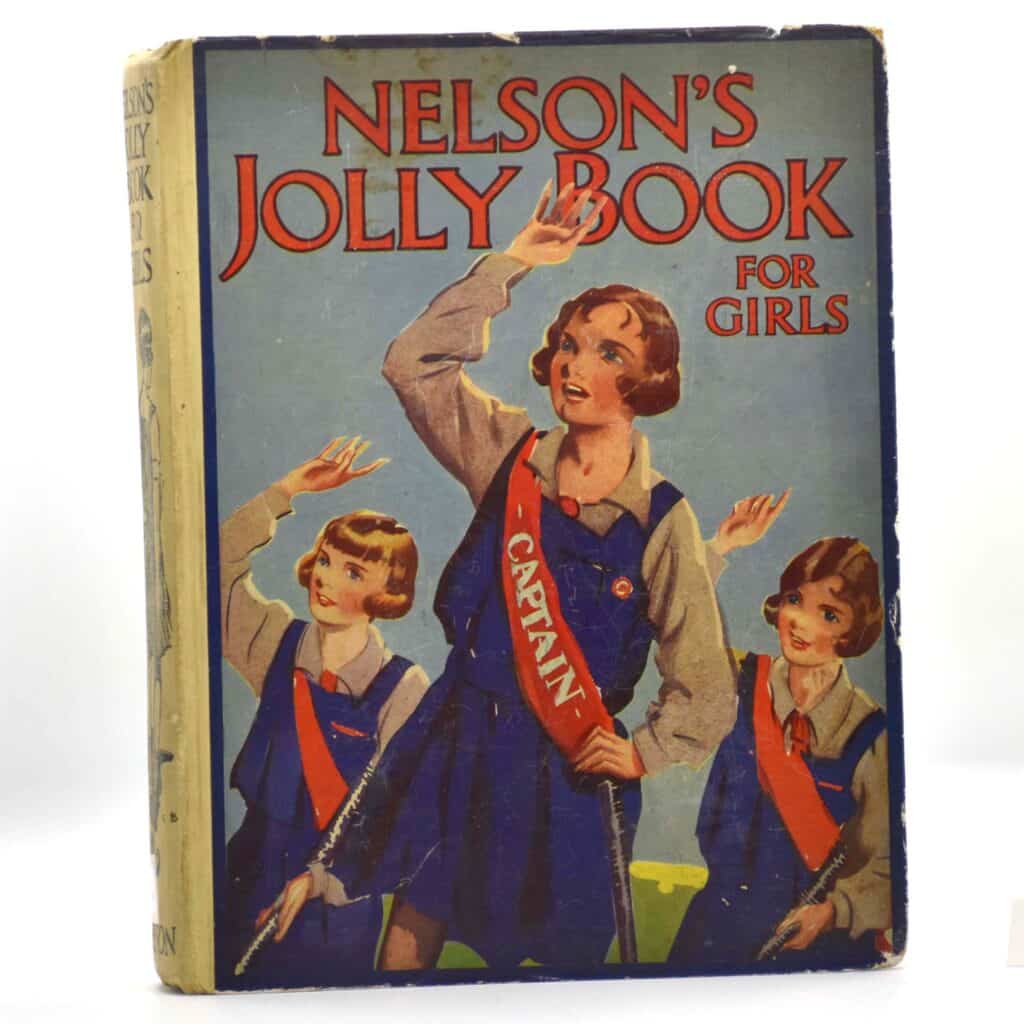 A picture of a book called Nelson's Jolly Book for Girls, depicting three girls on the cover in hockey uniform: a blur tunic over a white blouse with a red sash.