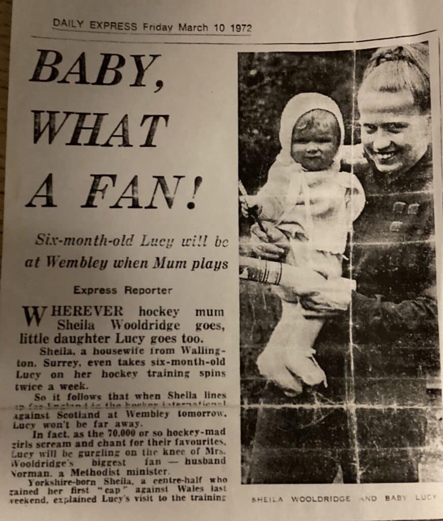 A newspaper cutting titled "Baby, What a Fan!" with a photograph of a woman holding a baby.