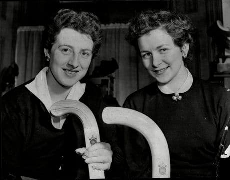 A black and white image of two women holding hockey sticks