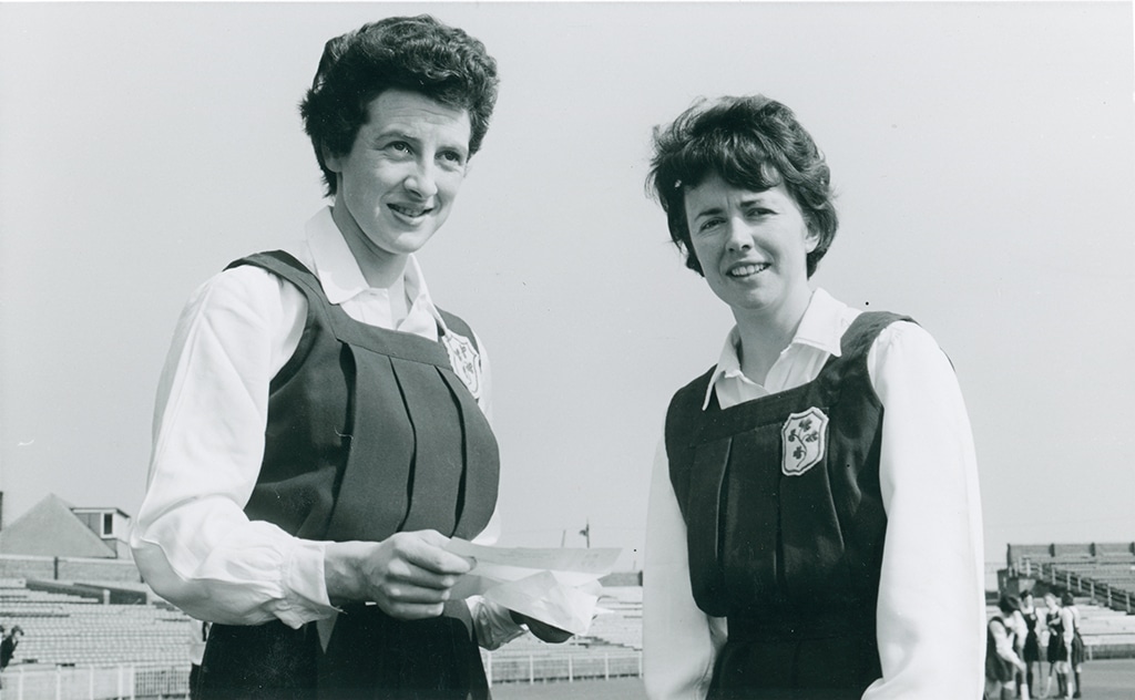 Two women in hockey uniformslooking at the camera in a black and white photo