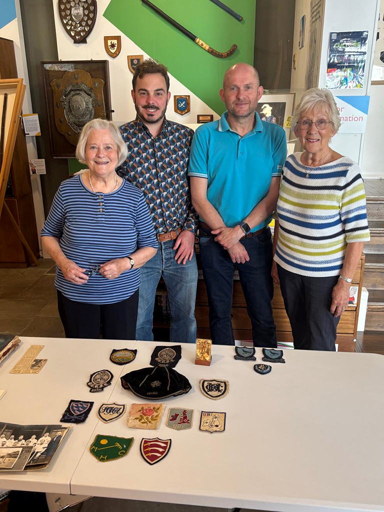 A colour photo of two men and two women standing in front of a table with hockey memorabilia laid out