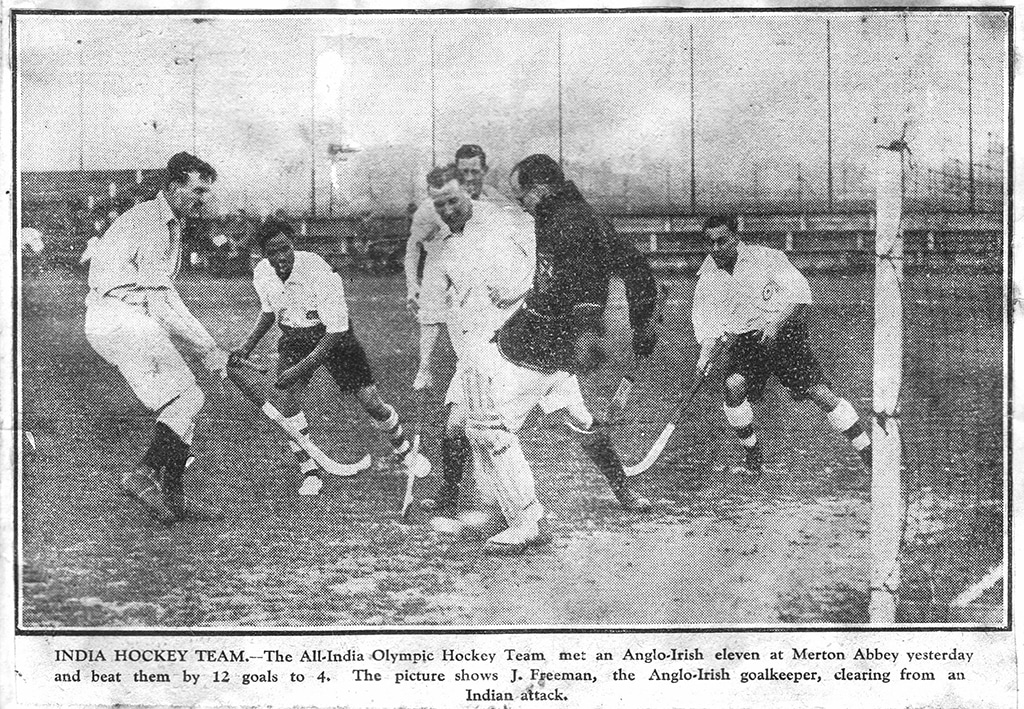 Black and white action photograph of a 1928 hockey match at Merton Abbey, capturing players in dynamic movement near the goal. The scene conveys intensity and competitive spirit.