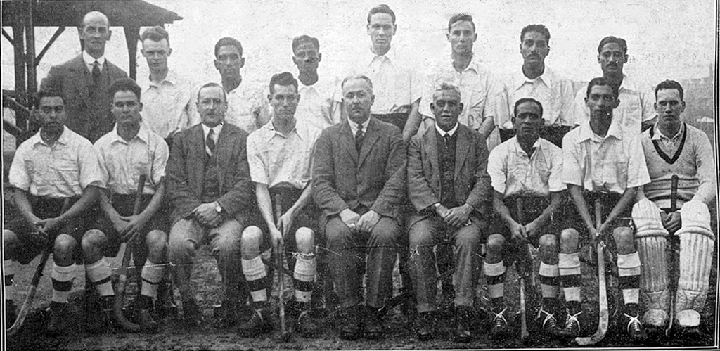 Black and white photograph of a men's hockey team from 1928, with players seated and standing in formal rows, holding hockey sticks. Their attire and composed postures reflect the athletic pride and dedication of the era.