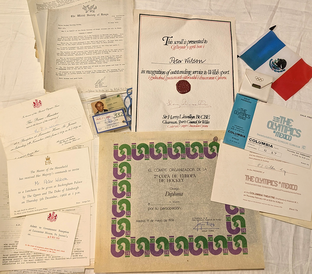 Collection of certificates, letters, and a flag on a cloth. Vintage, organized feel. Background plain. Evokes pride and historical significance.