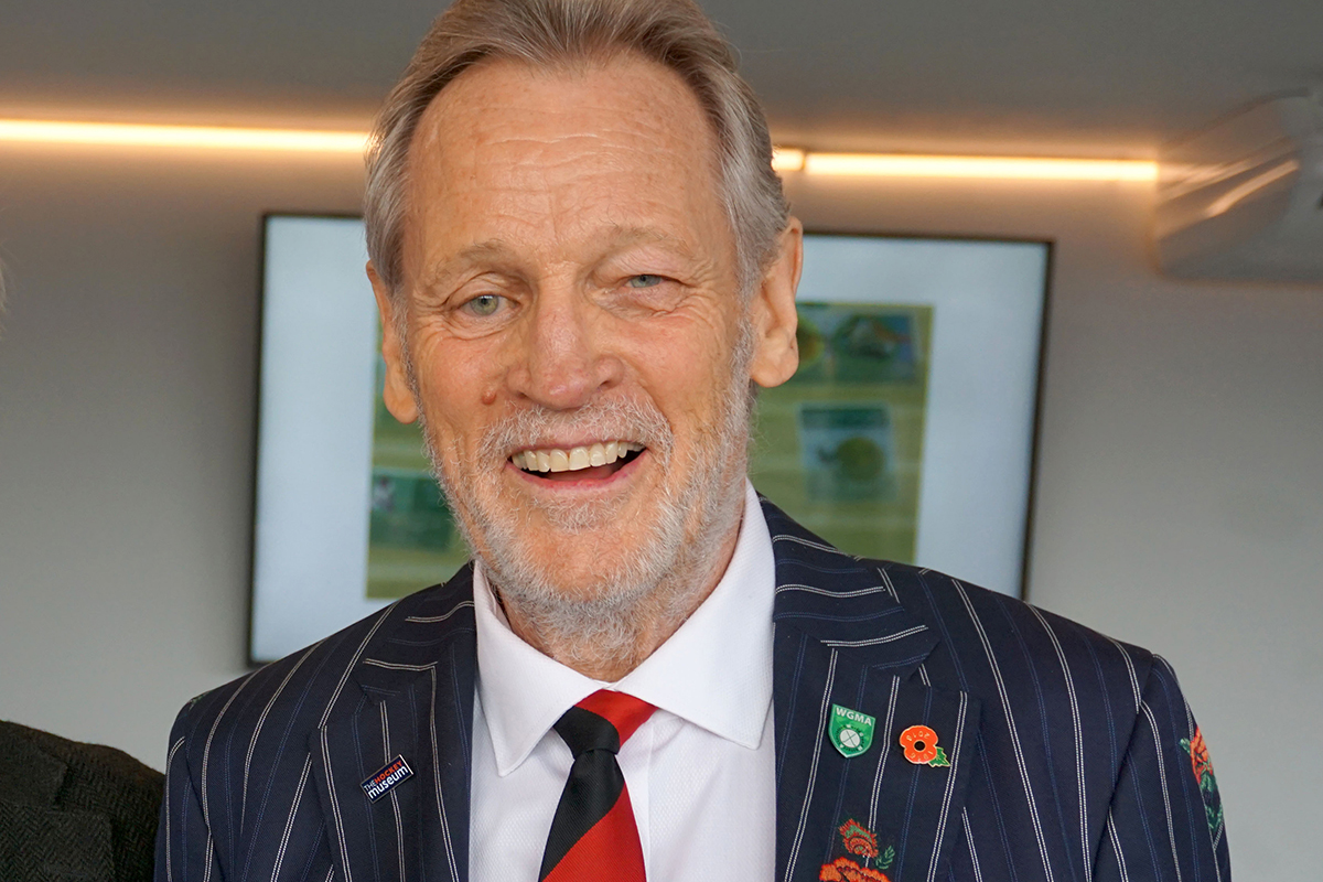 A head-and-shoulders photograph of a smiling middle-aged man wearing a suit and tie