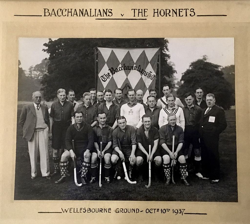 Black and white group photograph of two men's hockey teams standing or seated in three rows. Players are wearing buttoned-up shirts or sweaters. A large flag or banner is behind the players.