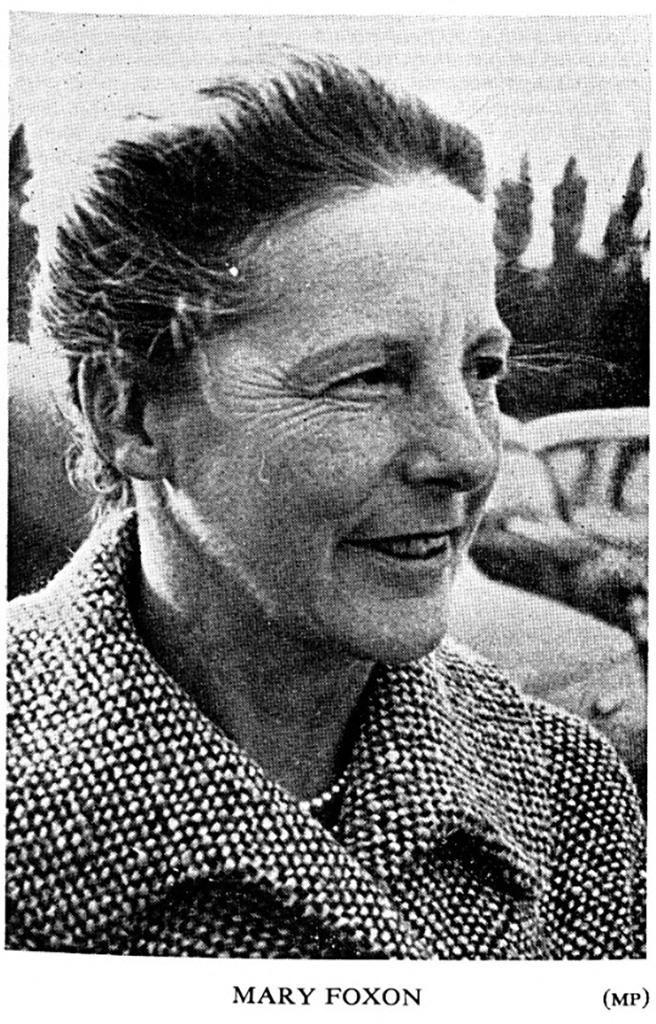 A woman in profile with her hair tied back wearing a big coat.