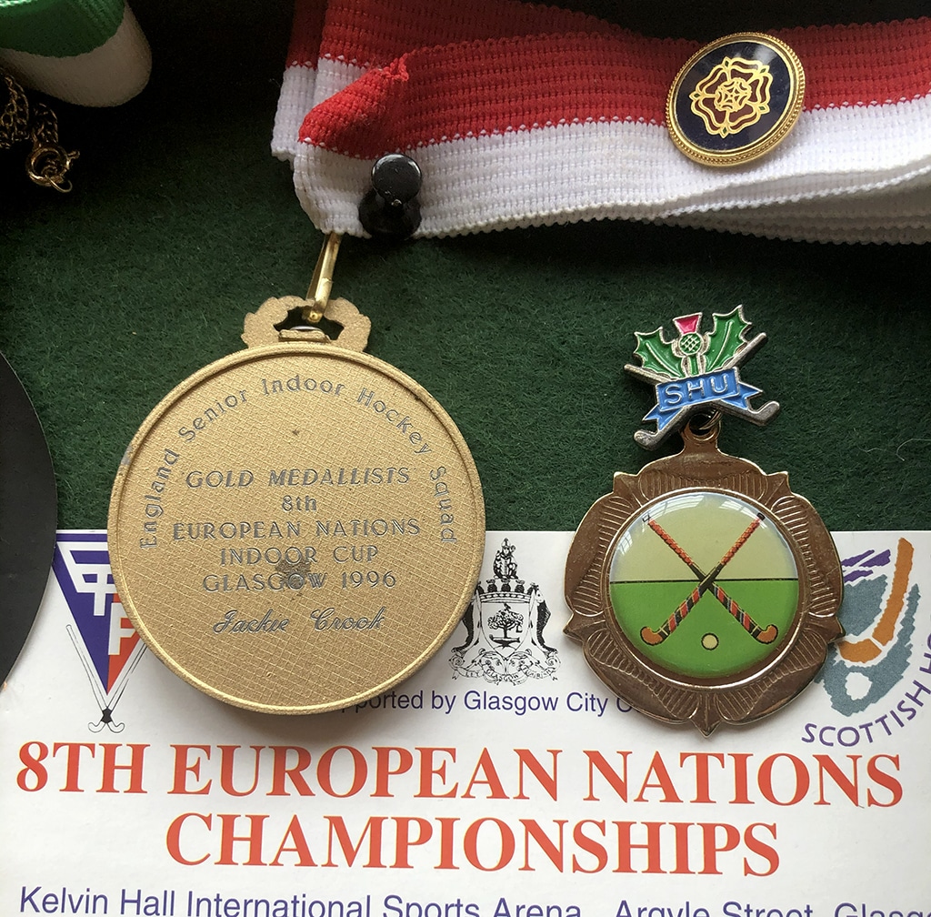 A small collection of memorabilia items: two medals with ribbons, two pin badges and a match programme.