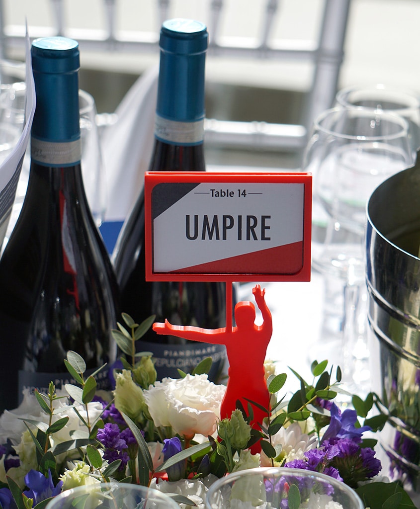 A floral table centrepiece with a hockey figure in the middle in front of wine bottles and glasses.
