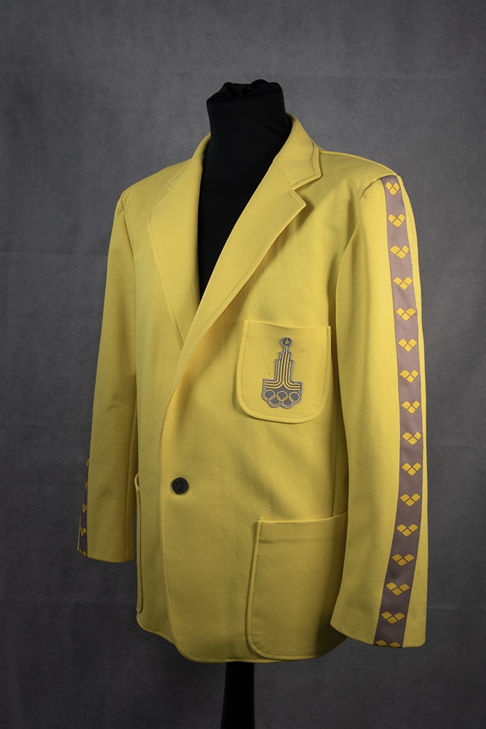 A bright yellow blazer on a mannequin against a dark grey background