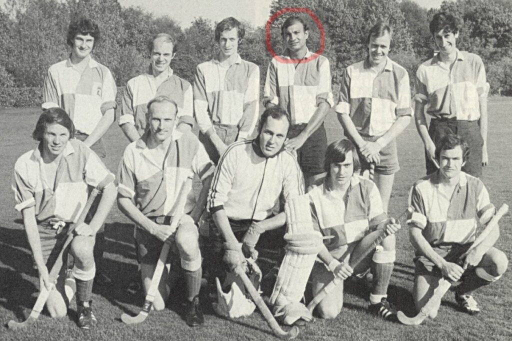 Black and white team photograph of men in two rows wearing chequered shirts and holding hockey sticks