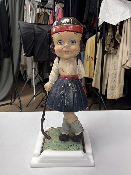 A sculpture of a doll-like girl wearing old-fashioned hockey clothing.