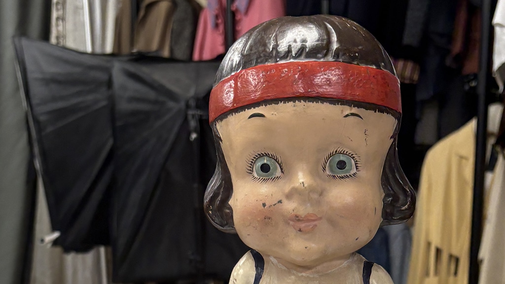 The head of a doll-like girl with brown hair and a red hairband.
