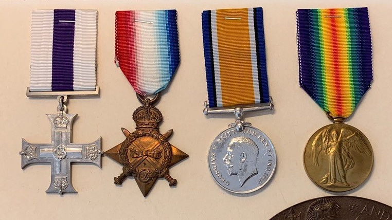Four medals of varying shapes and coloured ribbons