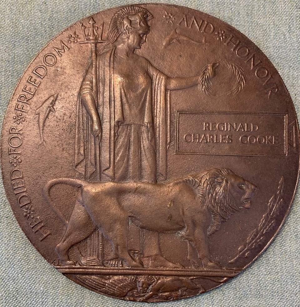 A bronze coloured medallion showing the female figure of Britannia alongside a male lion.