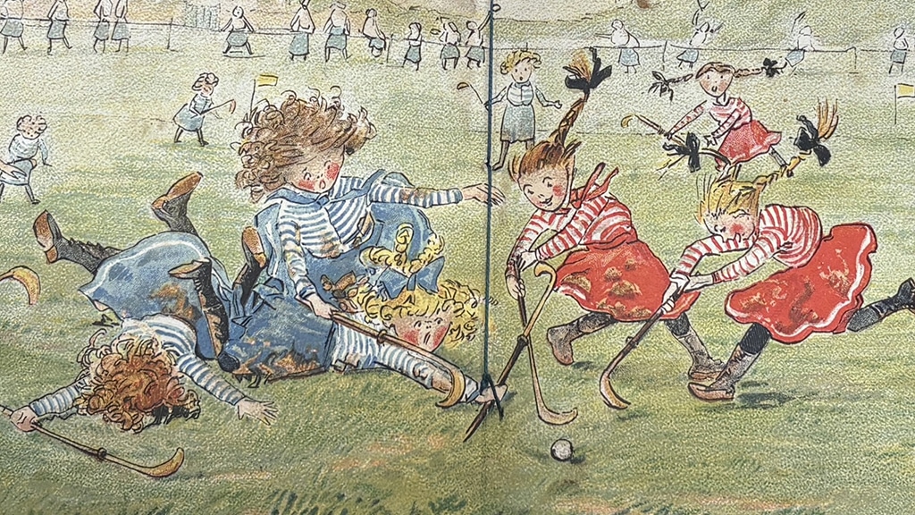 Mops vs Tails feature Illustration of a children's hockey match, with players in red and blue striped tops competing for the ball while several others tumble to the ground. Spectators line the edge of the hockey pitch in the background.